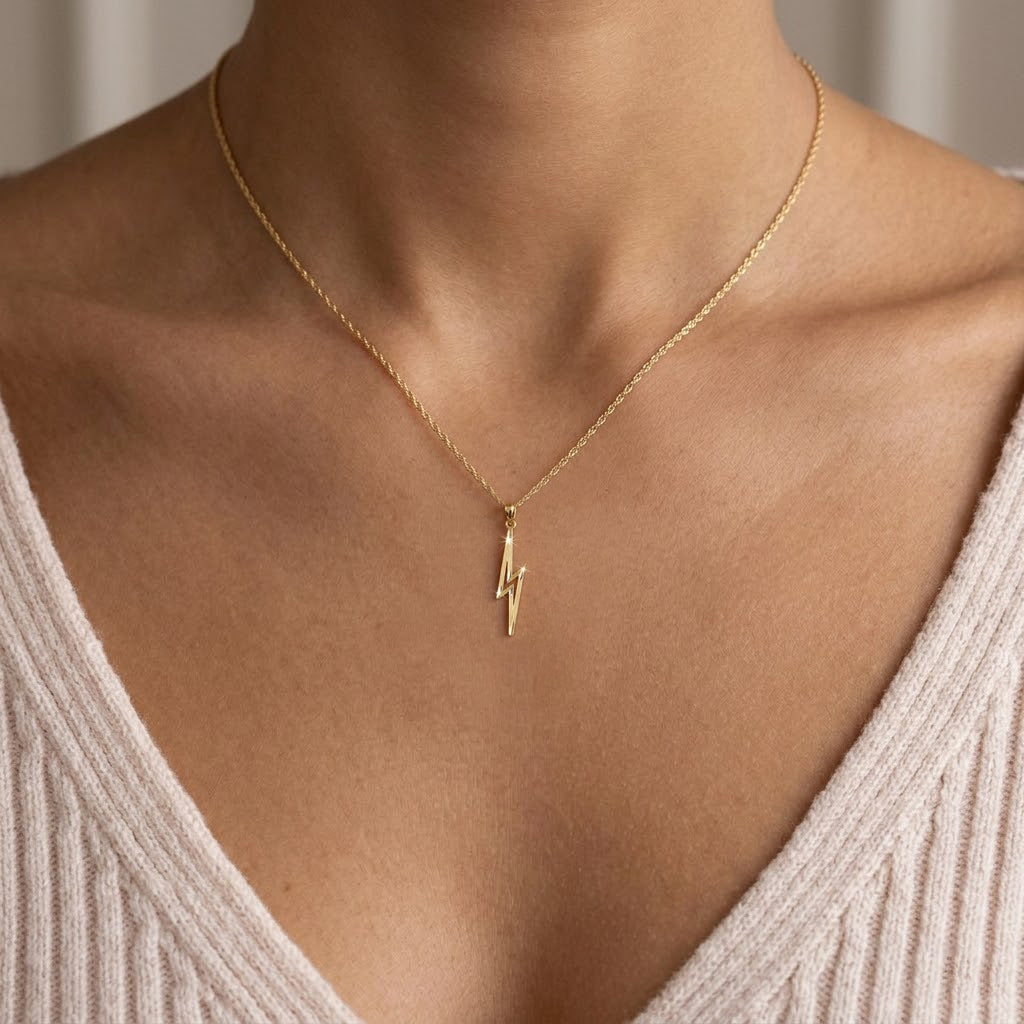 Gold lighting bolt pendant on a gold rope chain worn by female model 