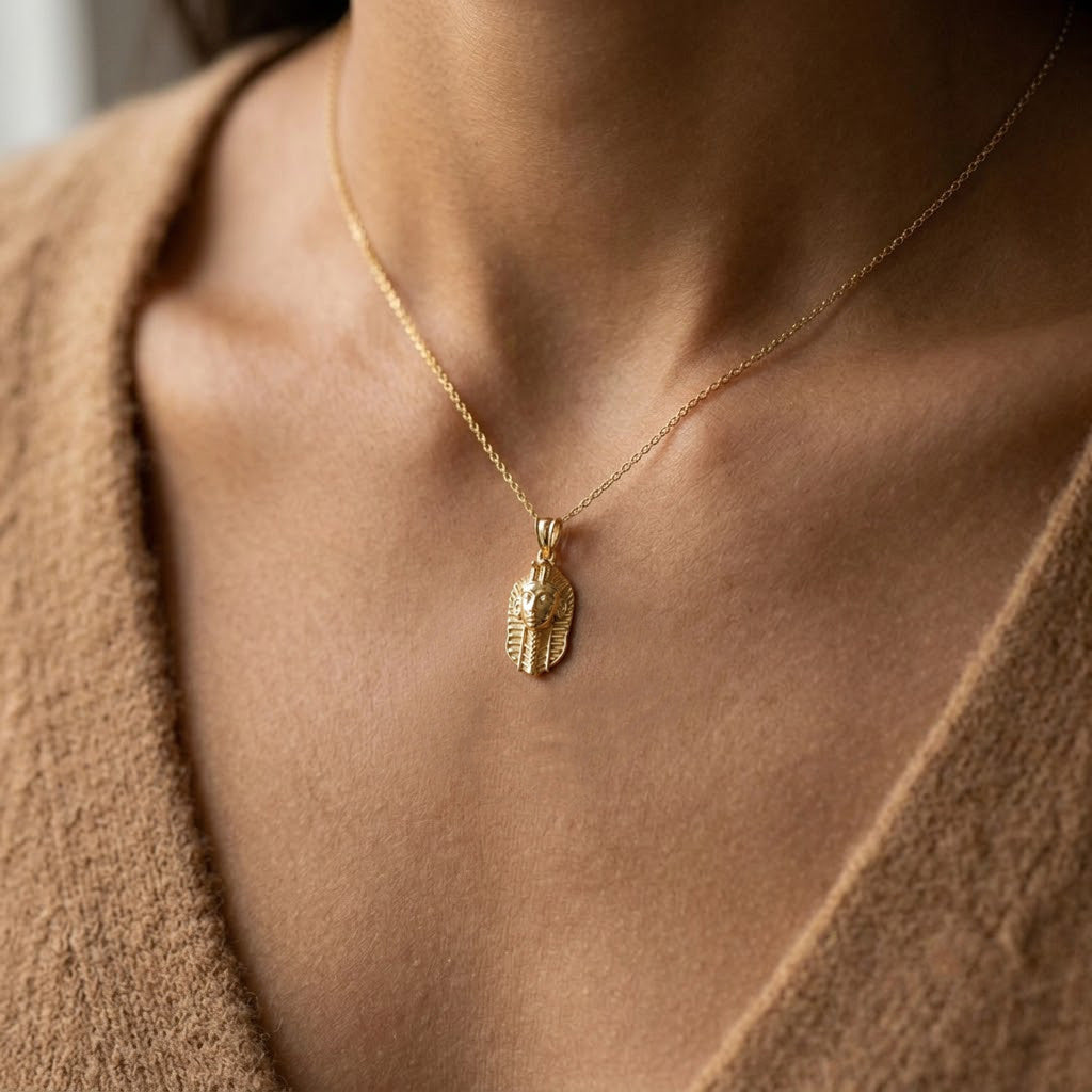 [group: 10k-gold]  Gold  ecklace with a Pharaoh  pendant on a person wearing a brown sweater.