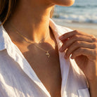 Female model wearing gold dolphin pendant with gold rope chain 