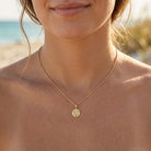gold sand dollar pendant worn by model 
