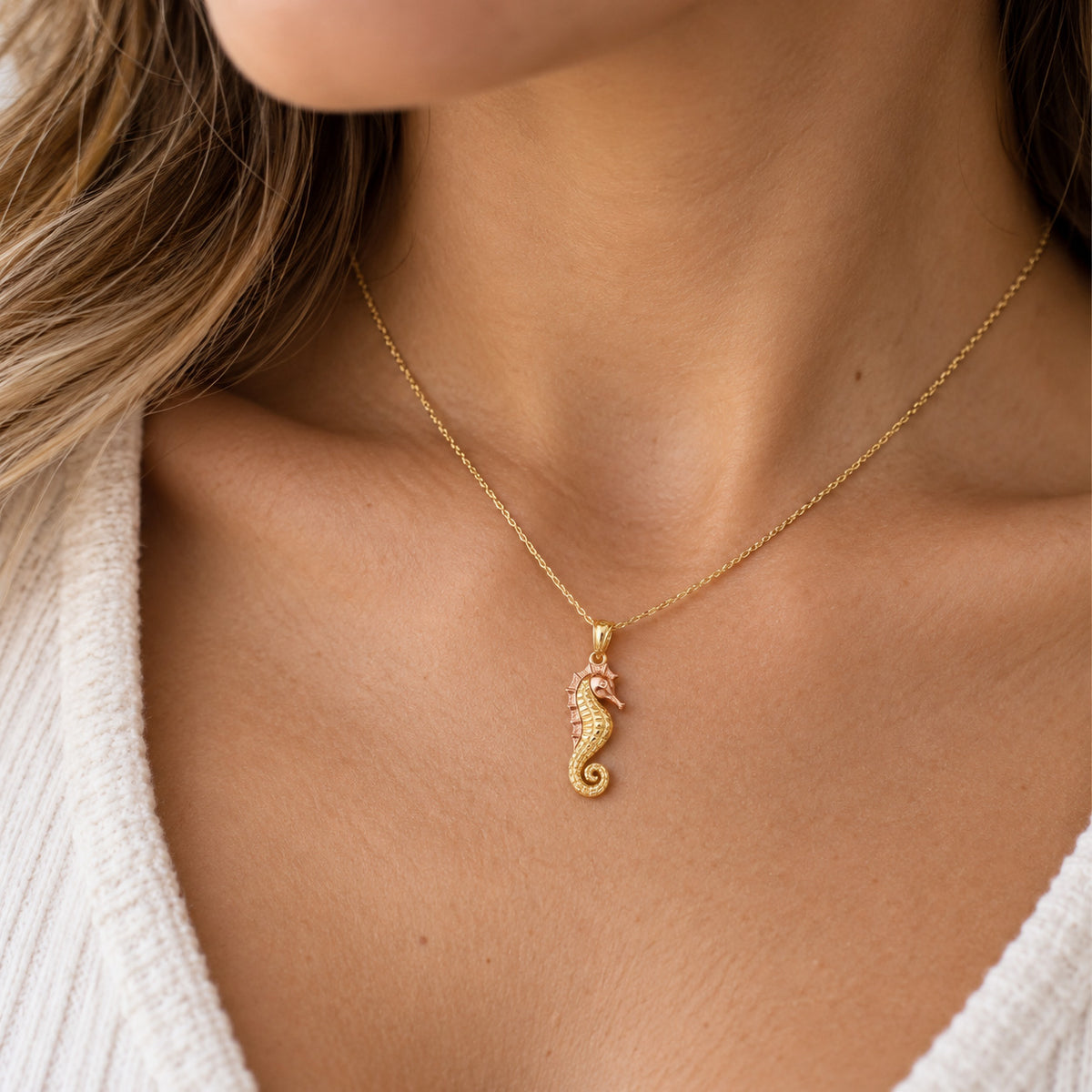 gold seahorse pendant worn on gold chain on female model 