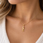 gold seahorse pendant worn on gold chain on female model 