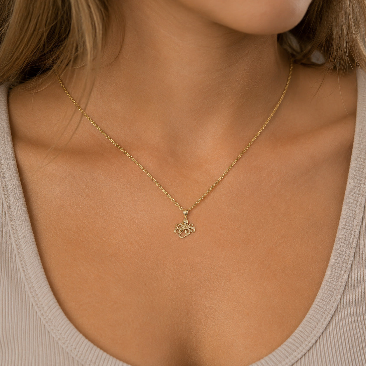 [group: small]A close-up of a model wearing a delicate gold chain necklace with a small, detailed horse-shaped pendant.