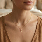 Gold cross pendant on gold chain worn by female model 