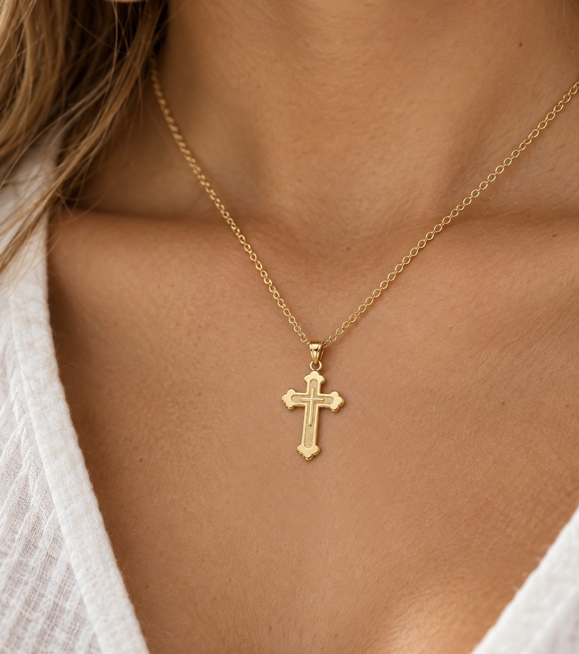 [group:gp] Gold cross pendant on a white background