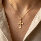 [group:10k-gold] Gold cross necklace on a person wearing a beige shirt