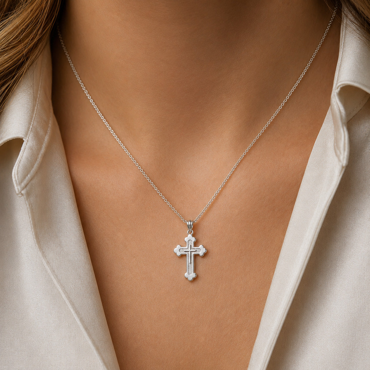 [group:silver] Silver cross necklace on a person wearing a beige shirt