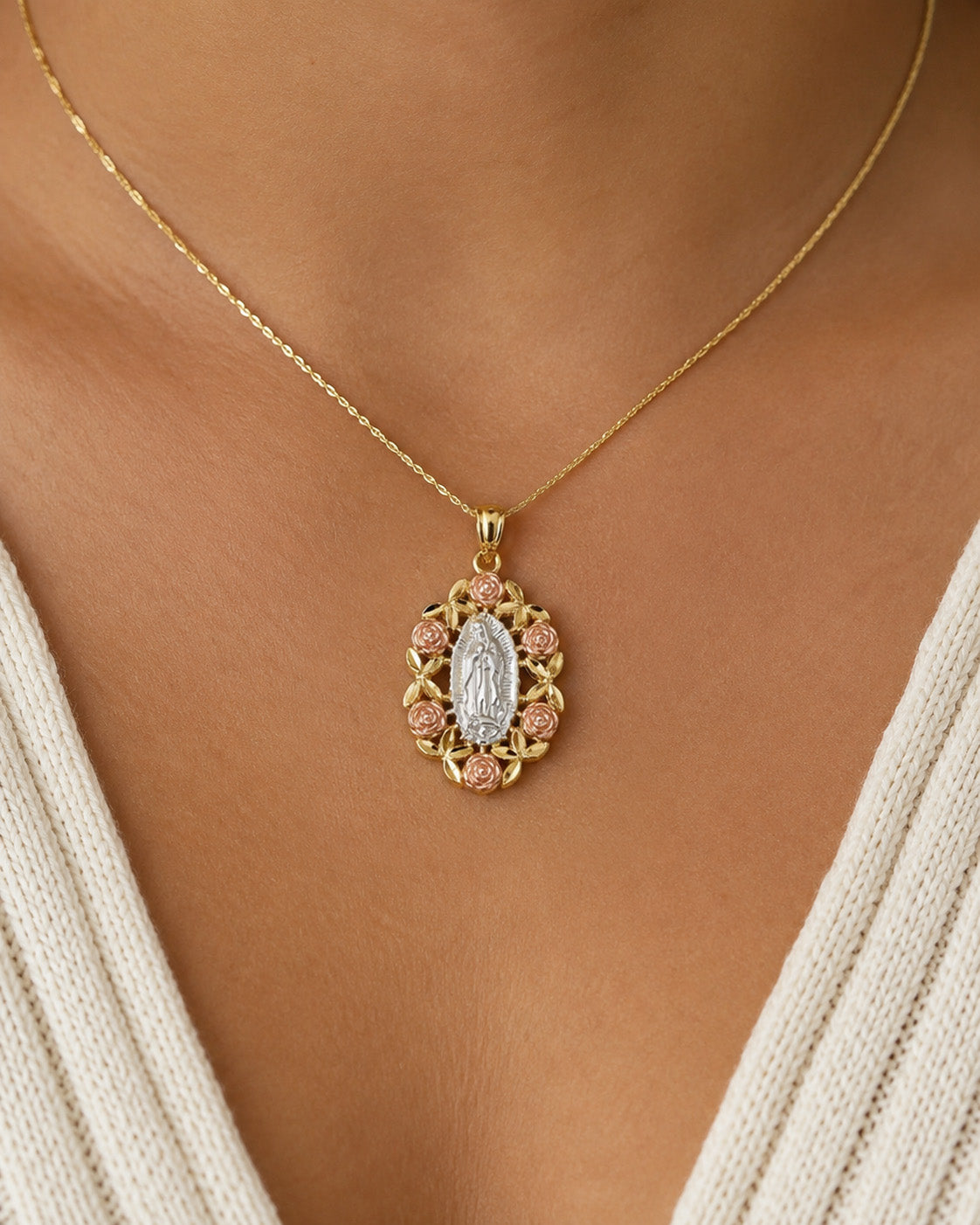 [group: large]A gold necklace with a Miraculous Medal pendant, worn on a model's neck. The pendant features a central silver-toned Miraculous Medal image surrounded by a gold border with small pink gemstones.