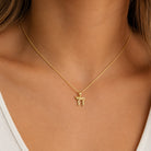 A close-up of a person's neck and chest wearing a delicate gold chain necklace with a small gold chai pendant
