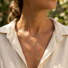 Close-up of a person wearing a gold necklace with a cross pendant, outdoors.