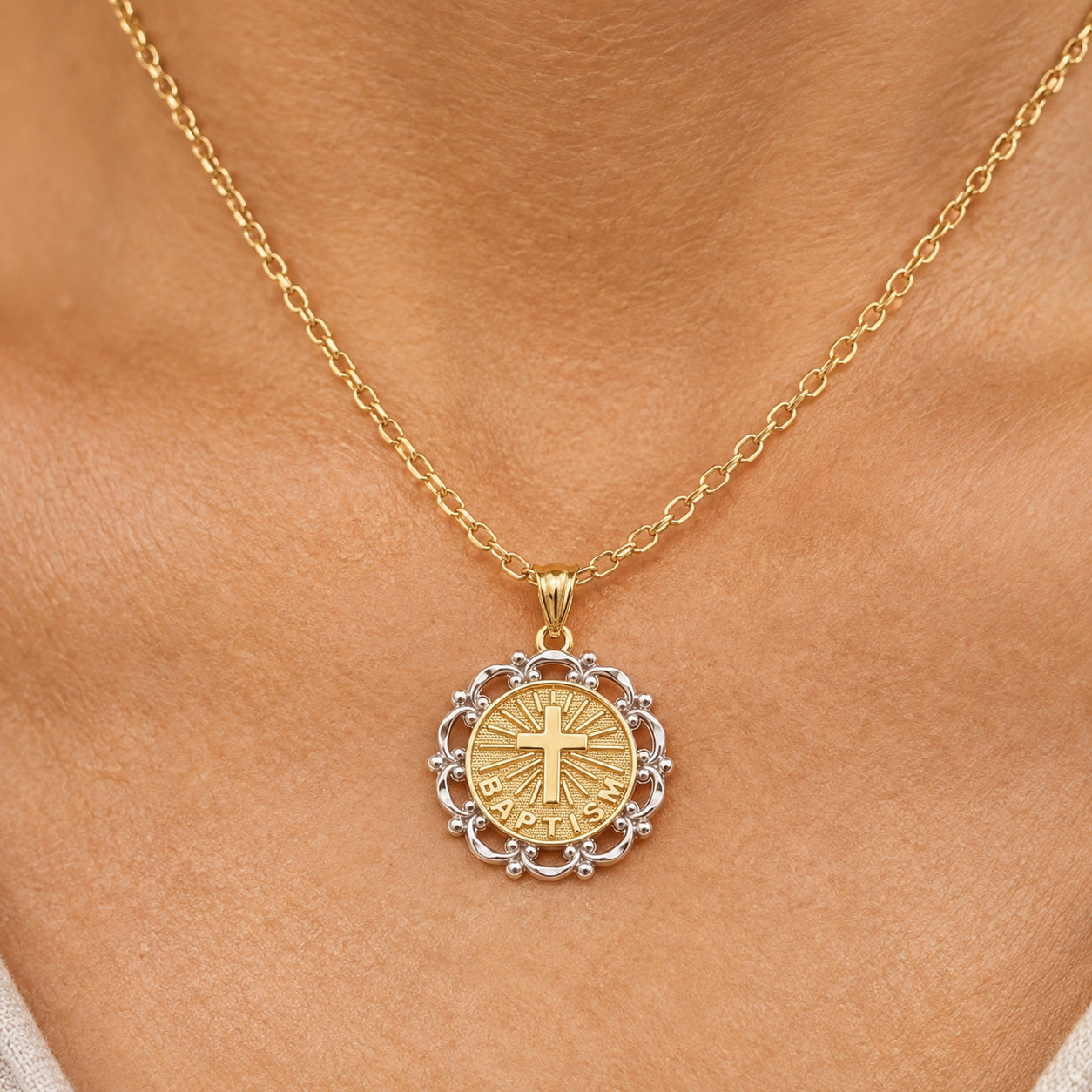 [group: 10k-gold] A gold and silver pendant necklace worn on a person's neck, featuring a round gold pendant with a cross and 'INRI' inscription, surrounded by a silver filigree border.
