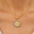 [group: 10k-gold] A gold and silver pendant necklace worn on a person's neck, featuring a round gold pendant with a cross and 'INRI' inscription, surrounded by a silver filigree border.