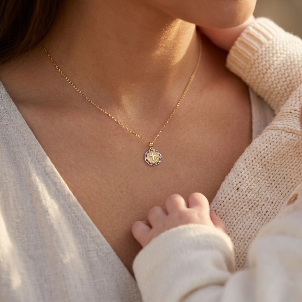 [group: gold-plated] Close-up of a person wearing a gold necklace with a pendant, holding a baby.