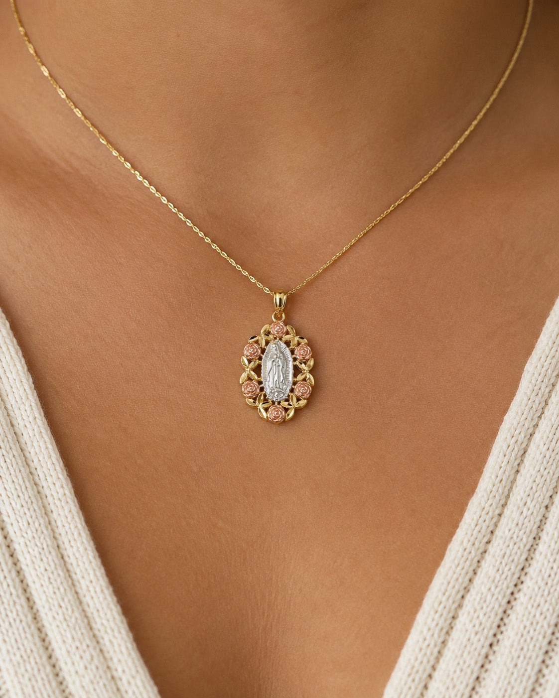 [group: small]A gold necklace with an oval Miraculous Medal pendant, worn on a model's neck over a cream-colored knit top.