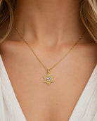 A gold Star of David pendant necklace with a central clear gemstone, worn on a model's neck over a white top.
