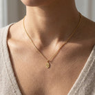Gold Oval Religious Cross Pendant on gold chain worn by female model 