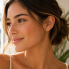 A close-up of a woman wearing a small gold Star of David stud earring, shown in profile against a softly blurred indoor background.
