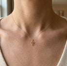 Gold necklace with a cross pendant on a person's neck