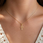 Gold Olive Branch Cross Pendant worn by female model with gold rope chain 