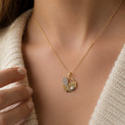 [group: 10k-gold]Gold necklace with a tennis-themed pendant on a person wearing a beige sweater.