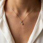 Gold necklace with a golf bag pendant on a person wearing a white shirt.
