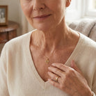 [group: gold-plated] Woman wearing a gold necklace with a heart pendant indoors.