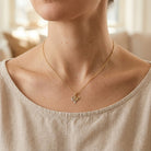 Necklace with a heart pendant worn by a person in a beige top.