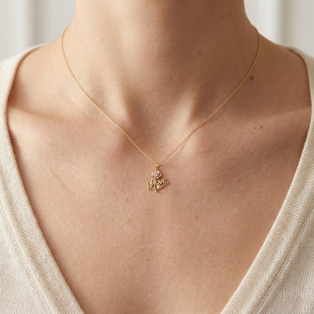 A delicate gold chain necklace with a small floral pendant worn on a model's neck, paired with a cream-colored knit top.