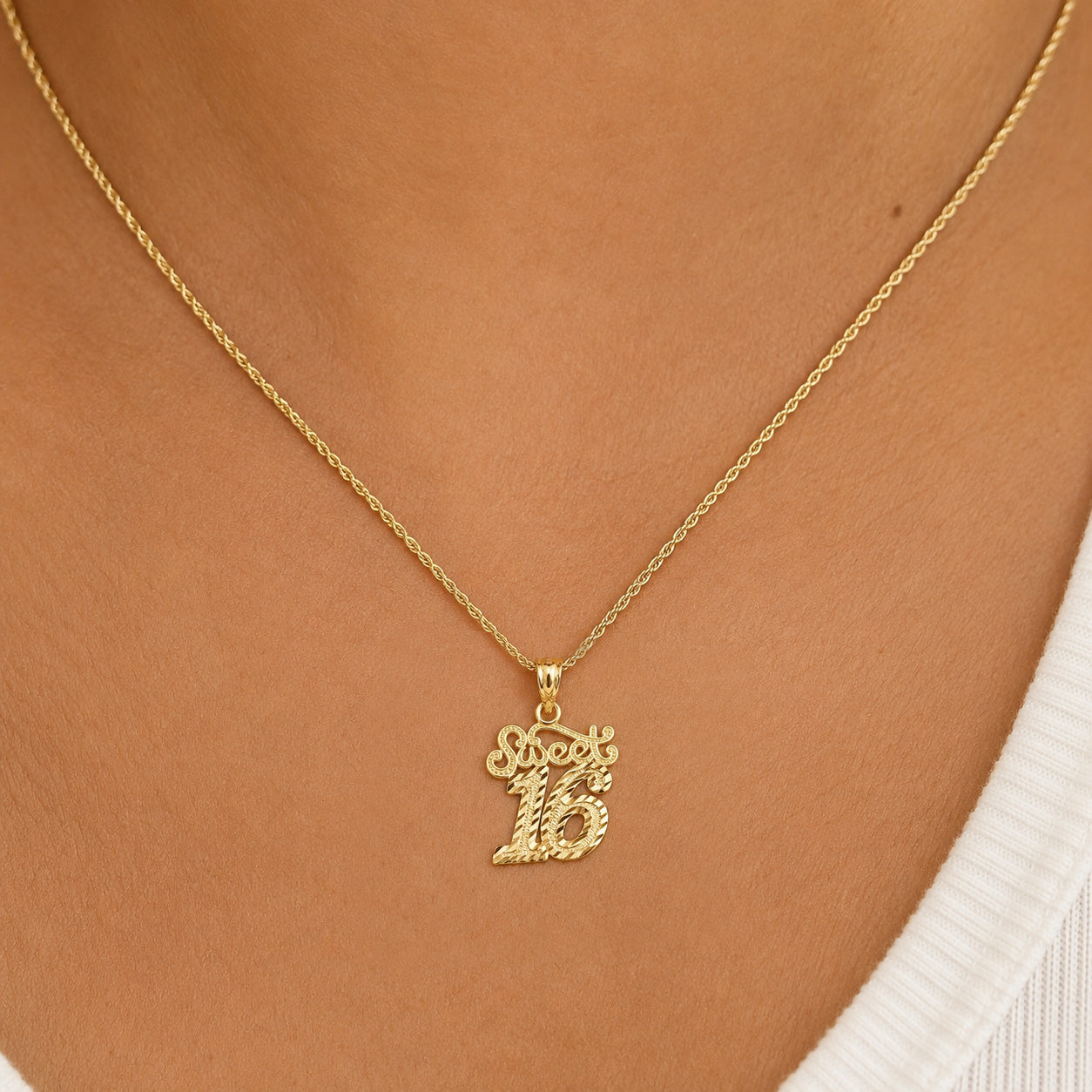 A gold chain necklace with a '16' initial pendant spelling out 'Sophia' in cursive, shown worn on a model's neck.