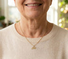 Woman wearing a gold necklace with a abulea pendant